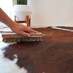 Hand brushing a natural cowhide rug for maintenance and cleaning