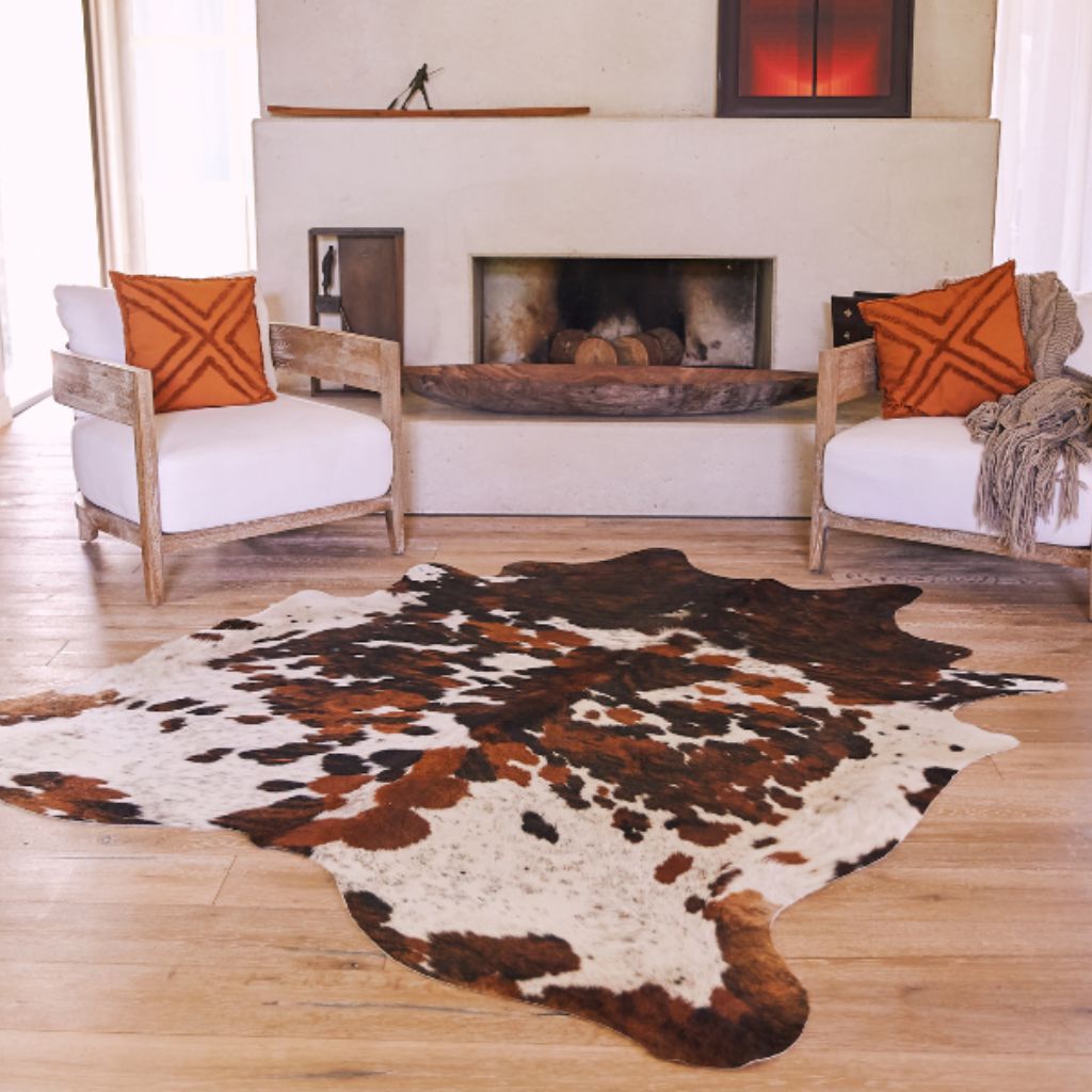 Cowhide rug laid on the floor in a stylish living room, adding warmth and texture to the space