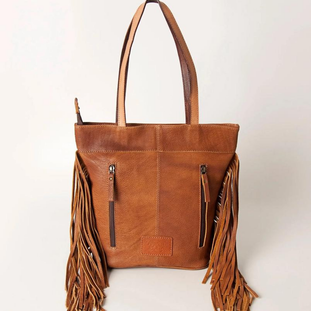 Back view of a hair-on cowhide leather tote with double concealed carry zipper pockets and leather fringes by American Darling