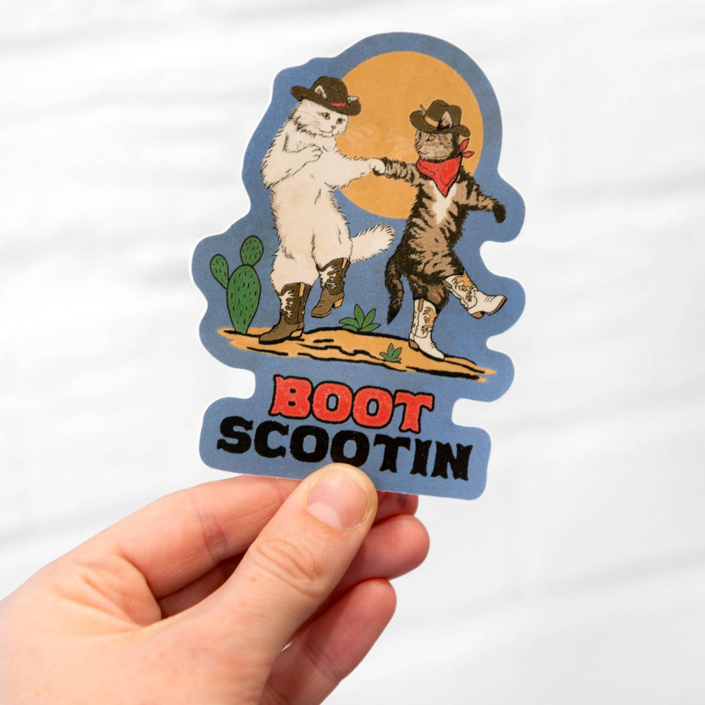 A hand holding a Boot Scootin Kitties sticker.