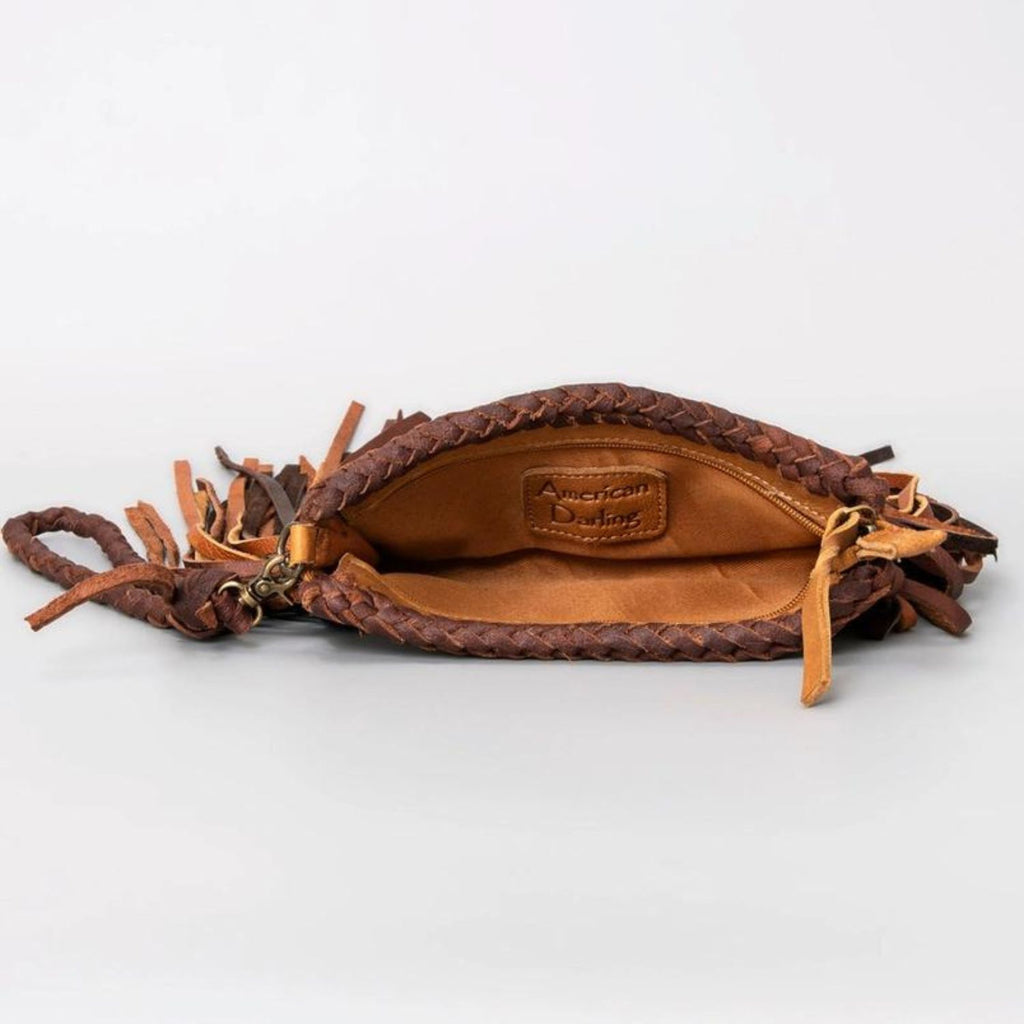 The interior of a western-style leather clutch featuring braided details and the "American Darling" brand logo stitched inside.