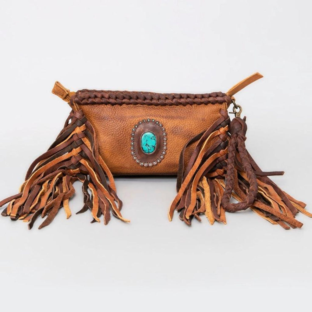 A rustic western-style genuine leather clutch with braided details, fringes, and a turquoise stone centerpiece.