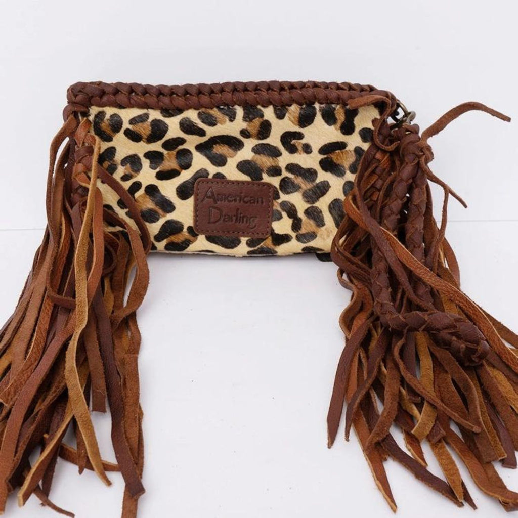 The back of a handcrafted leopard print hair-on leather clutch with long fringes and a stitched American Darling brand patch.