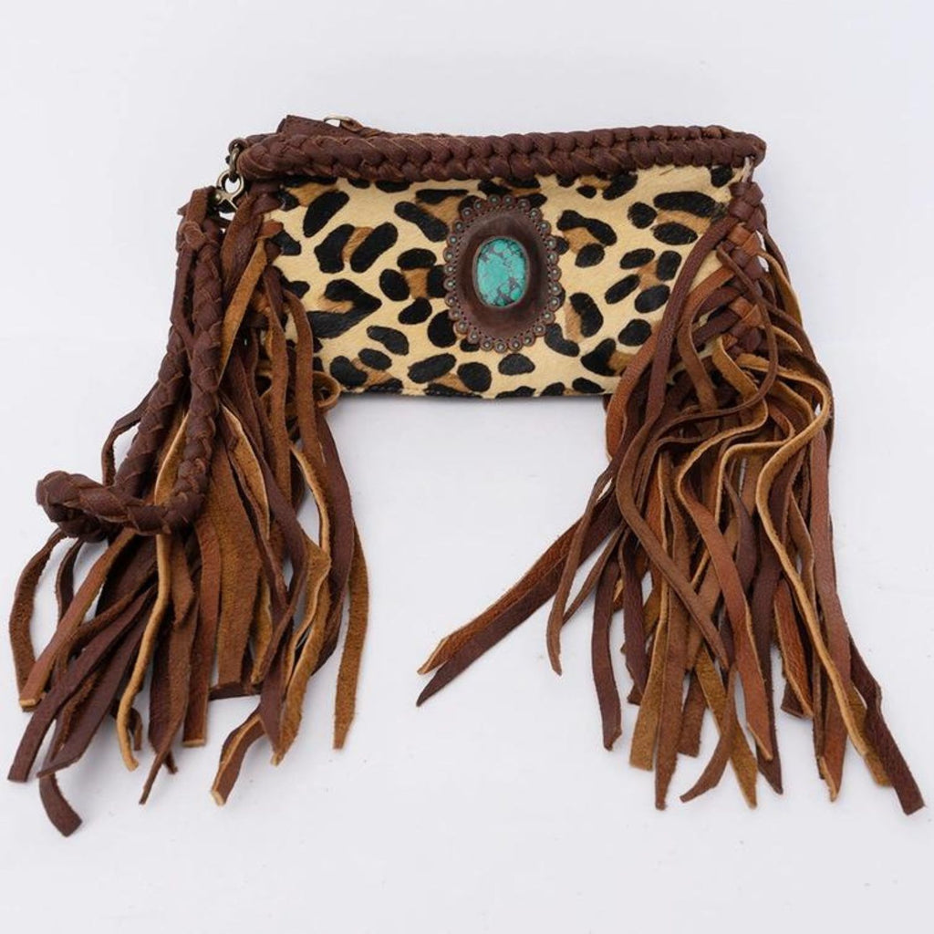 A handcrafted western-style clutch featuring leopard print hair-on leather, long fringes, and a turquoise stone centerpiece.