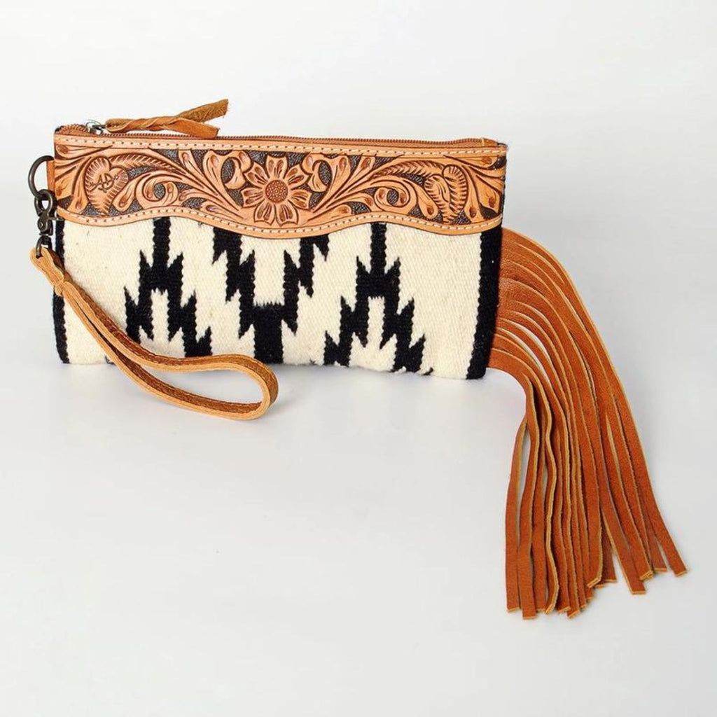 Front view of the Frontier Fringe Leather Wristlet with hand-tooled floral leather and black and white woven pattern.