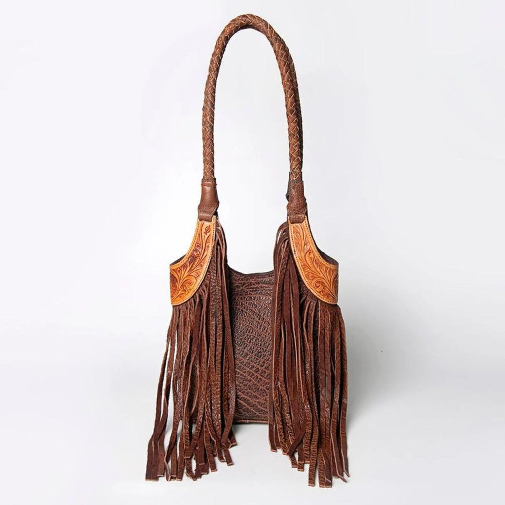 Front view of a hand-tooled leather Western tote bag with braided straps and long leather fringes, showcasing the detailed tooling and western design.