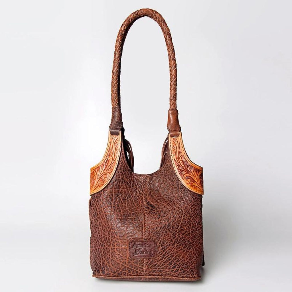 Back view of a hand-tooled leather Western tote bag, featuring braided straps and intricate leather craftsmanship with a rugged western style.