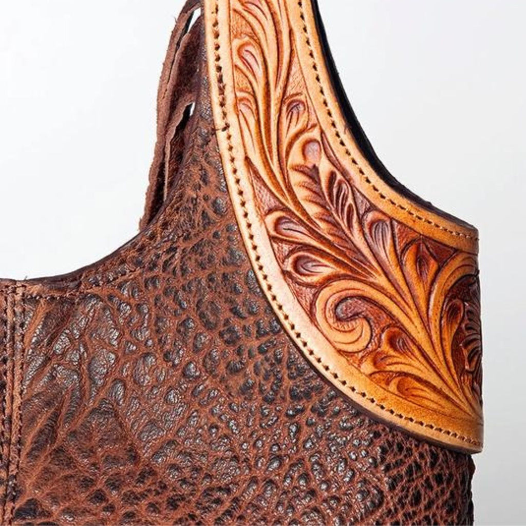 Close-up of the detailed hand-tooled leather design on a Western tote bag, highlighting intricate craftsmanship and premium full-grain leather texture.