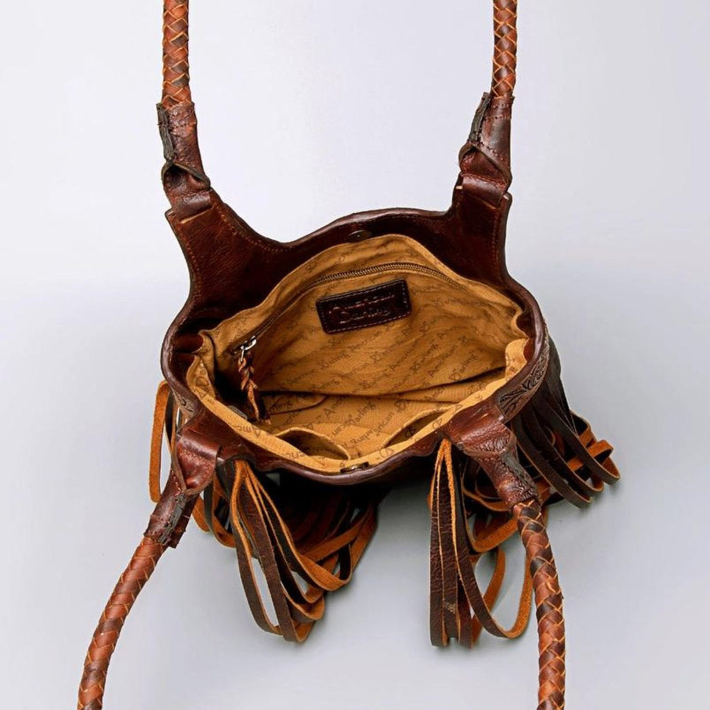 Interior view of a hand-tooled leather Western tote bag showing the spacious compartment with branded lining and zippered pocket.