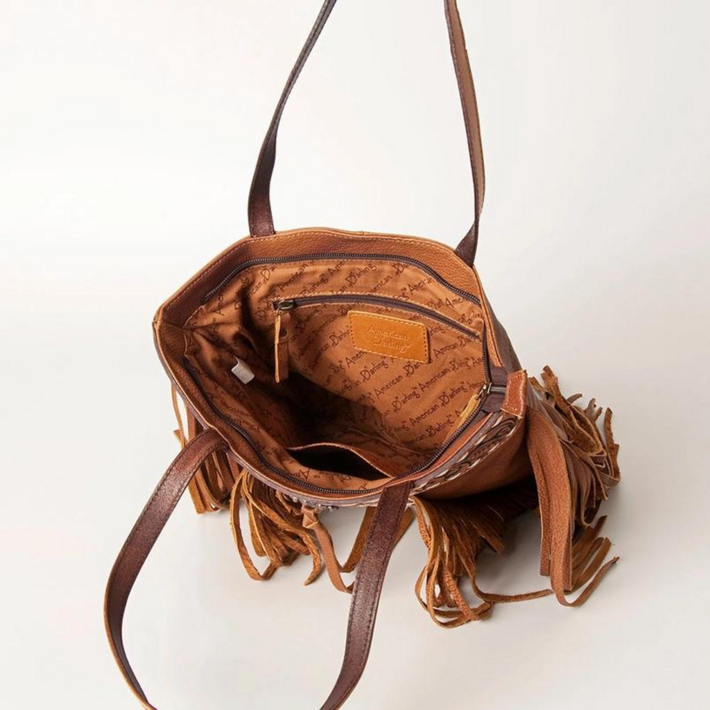 Interior view of hair-on cowhide leather tote bag featuring a zippered pocket and branded fabric lining by American Darling.