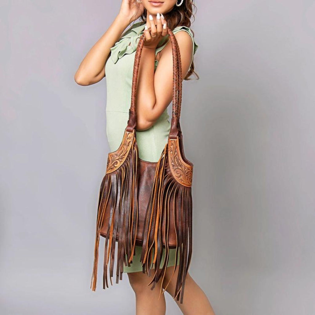 Model showcasing a hand-tooled leather fringe Western tote bag with intricate shoulder strap and detailed craftsmanship.