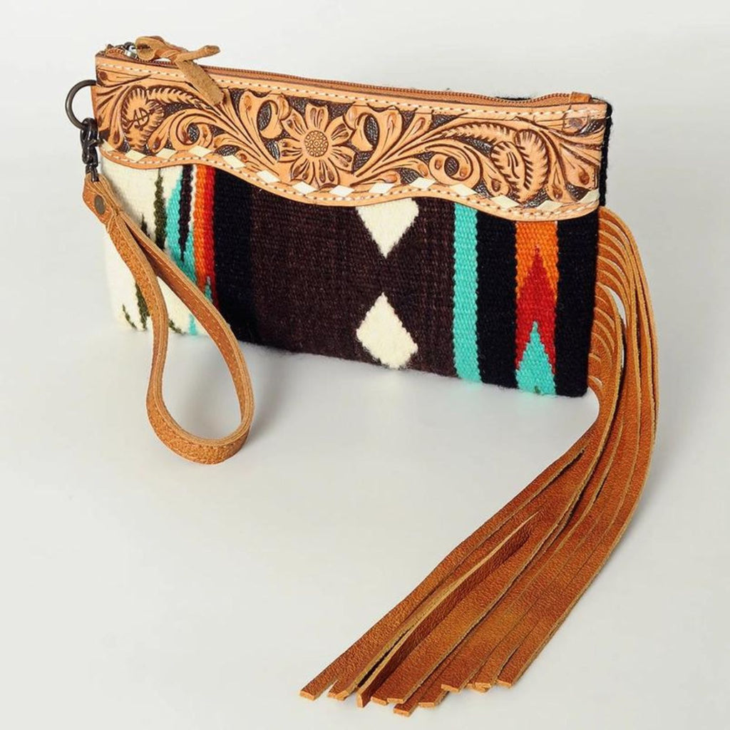 Mustang Mesa Handwoven Wristlet featuring a rich brown wool fabric with vibrant geometric patterns, hand-tooled leather accents, and long leather fringe.