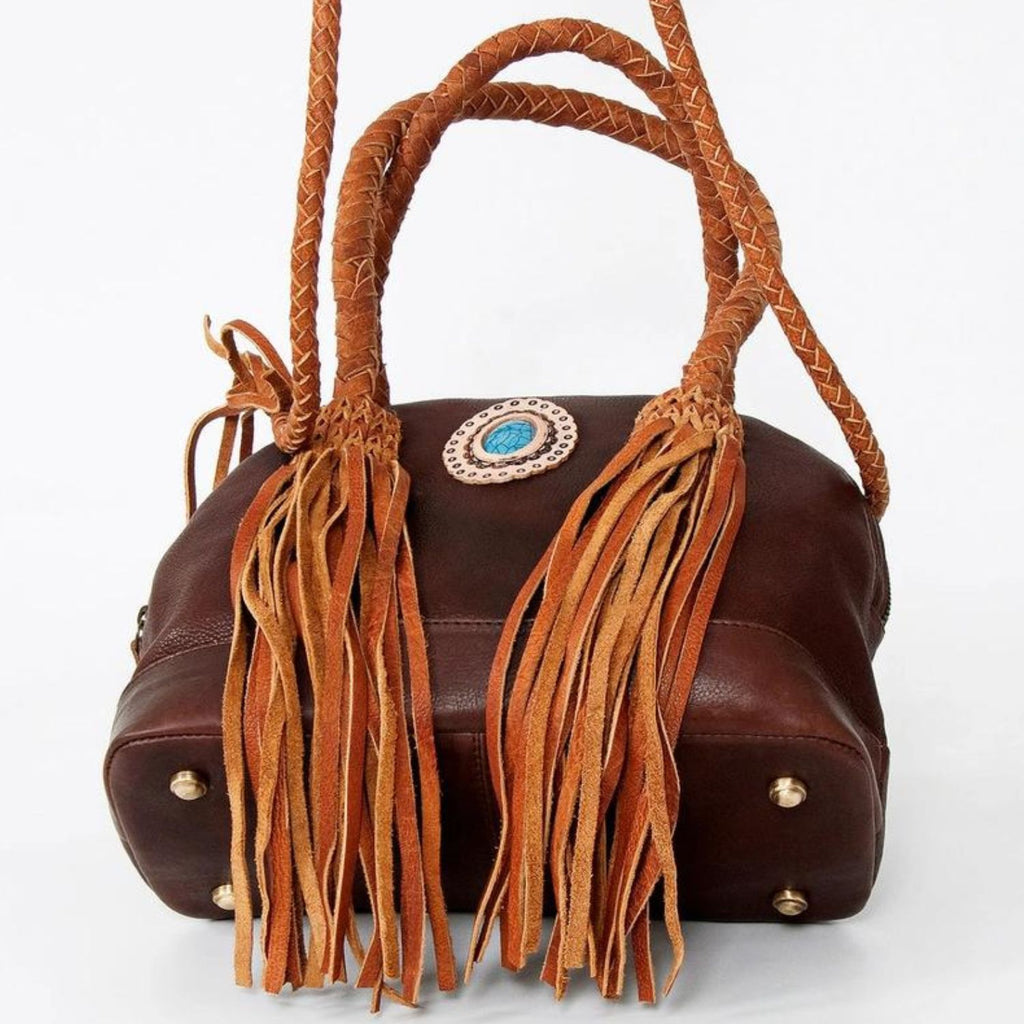 Bottom view of the Turquoise Trail Fringed Leather Tote showcasing its sturdy base, braided handles, leather fringe, and turquoise stone embellishment.