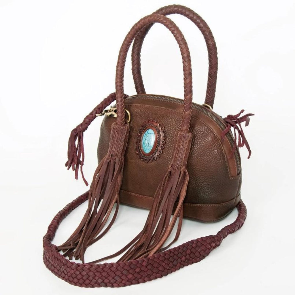 Angled view of a variant of the Turquoise Trail Fringed Leather Tote, highlighting the braided handles, leather fringe, and turquoise stone detailing in a rich leather finish for a Western-inspired design.